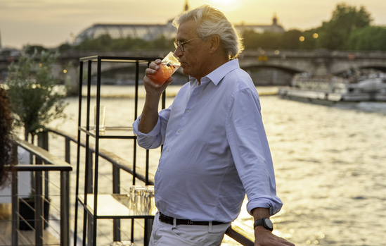 Invité savourant un cocktail au coucher du soleil sur la Seine